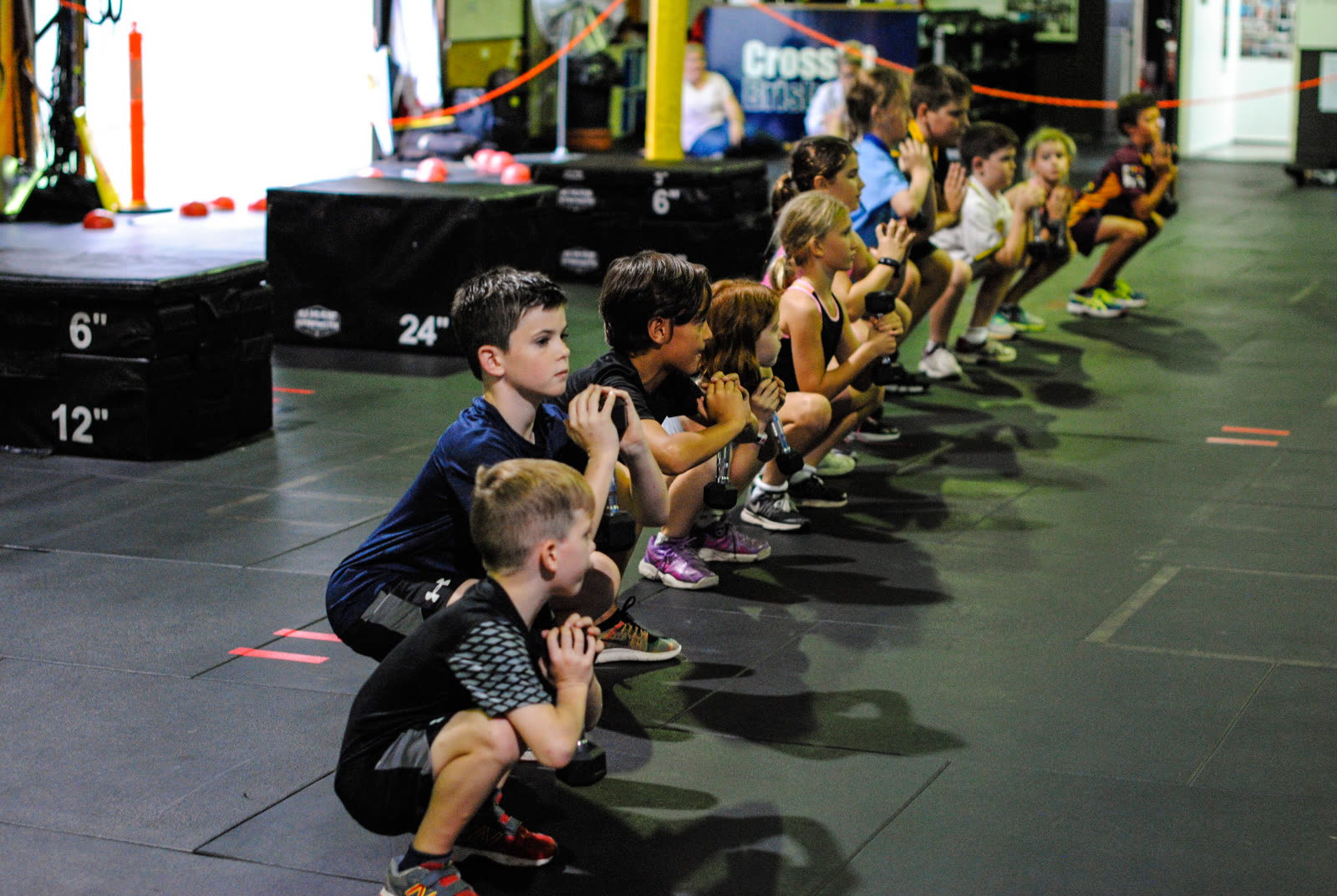CrossFit Brisbane kids squatting together during a kids fitness class